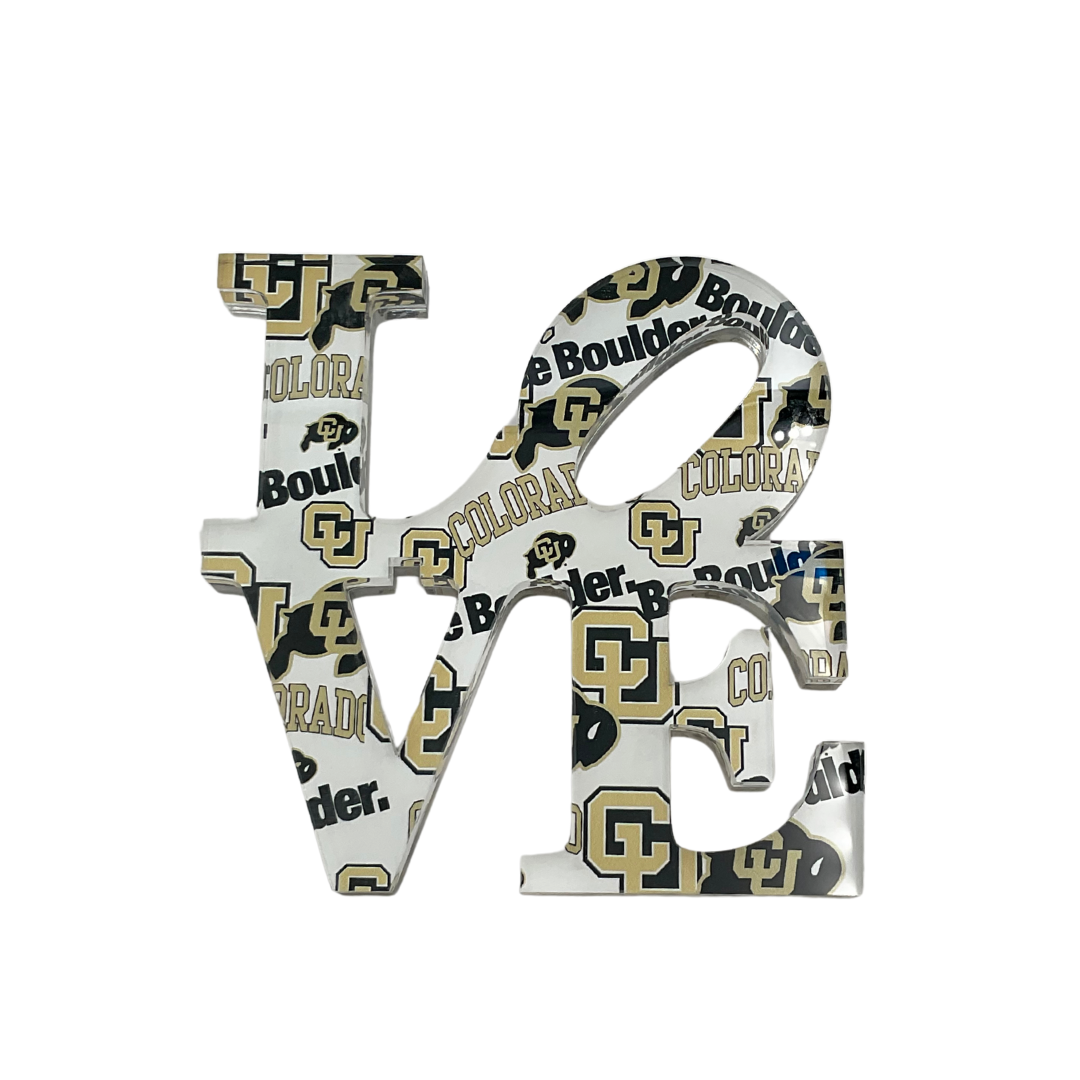 The Eye Candy College Love Sculpture is a decorative sign shaped as "LOVE" with University of Colorado Boulder logos in black, gold, and white—an ideal graduation gift or school collectible for any CU fan.