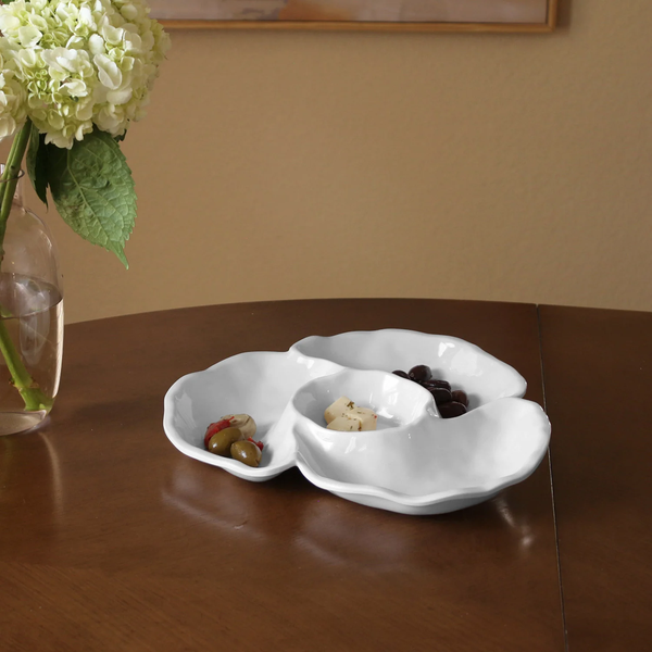 The Beatriz Ball Vida Havana Triple Dip Round Bowl holds assorted olives, cheese cubes, and grapes on a wooden table next to a vase with white hydrangeas.