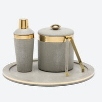 A gray stingray cocktail shaker, ice bucket with tongs, and the Blue Pheasant Langston Round Tray in Sand/Gold—an elegant serving piece with gold accents and a chic faux shagreen finish.