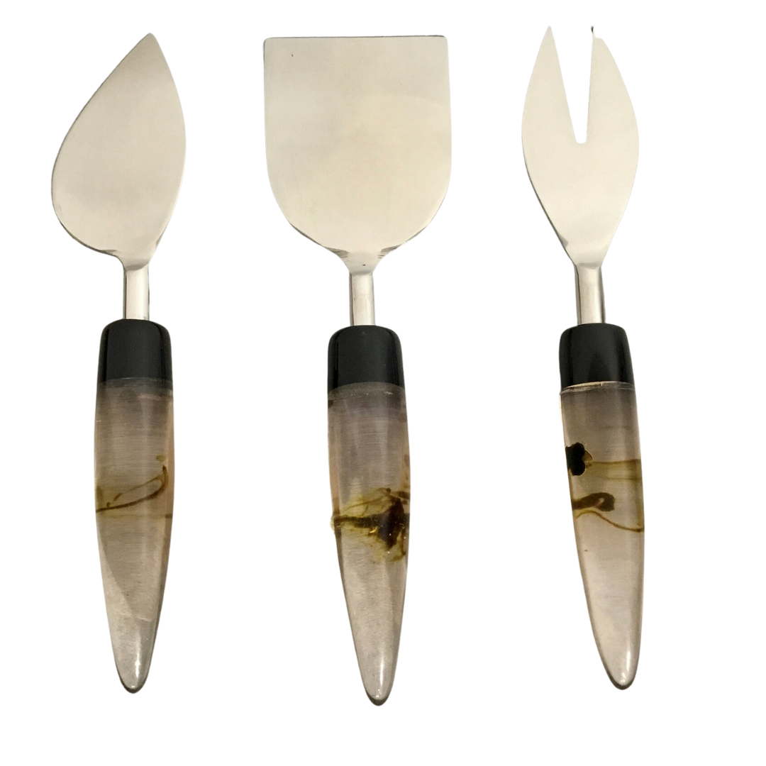 The India Handicrafts Lava Handle Cheese Knives Set includes three cheese knives with stainless steel blades and decorative resin handles, each featuring a unique blade shape for various kitchen needs, displayed vertically on a white background.