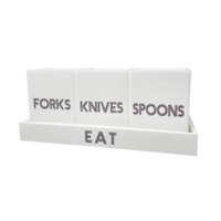 The Eye Candy Let's Eat Silverware Caddy in white with dark grey keeps your forks, knives, and spoons organized and accessible in labeled containers on a stylish matching tray for any countertop or table.