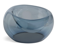 The Axiom Glass Caldera Vessel Medium 9" features a modern, transparent blue hand-blown glass design with a smooth, rounded, slightly asymmetrical shape—an eye-catching artisan decor piece for any space.