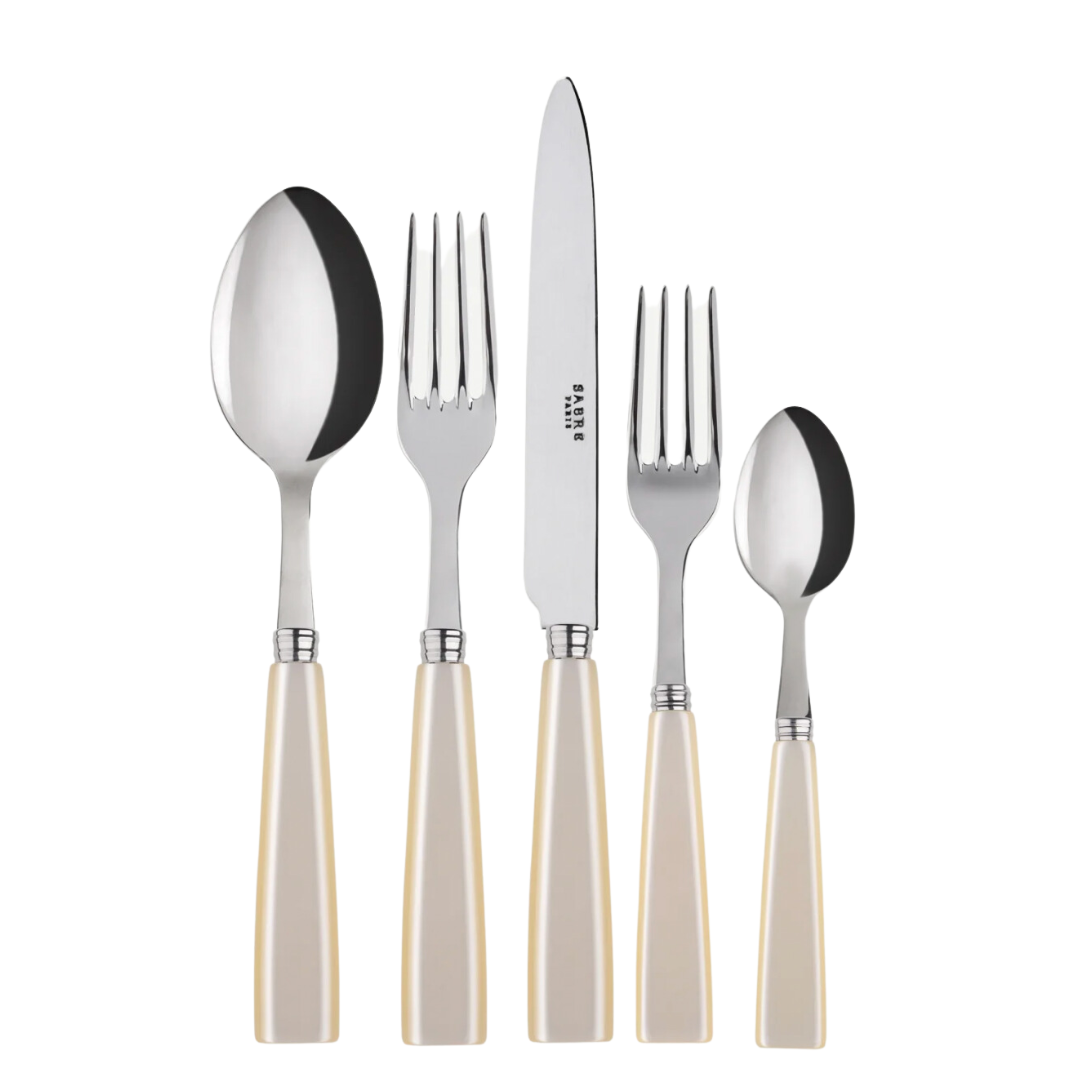 The Sabre Icone Flatware 5 Piece Setting includes a soup spoon, dinner fork, salad fork, dinner knife, and teaspoon with cream handles and polished 18/10 stainless steel tops displayed side by side on a white background.