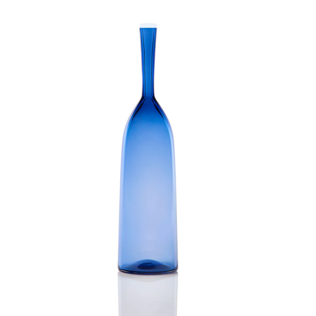 The Angelic Bottle - Small - by Cariati is a slender blue glass bottle with a narrow neck and smooth surface, showcased on a white background with a subtle reflection at its base.
