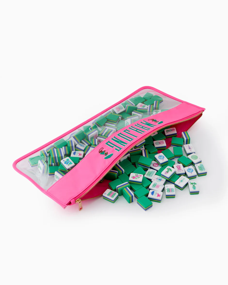 Oh My Mahjong’s pink zippered Mahjong Tile Bag with a clear section displays green and white tiles, some adorned with colorful designs.