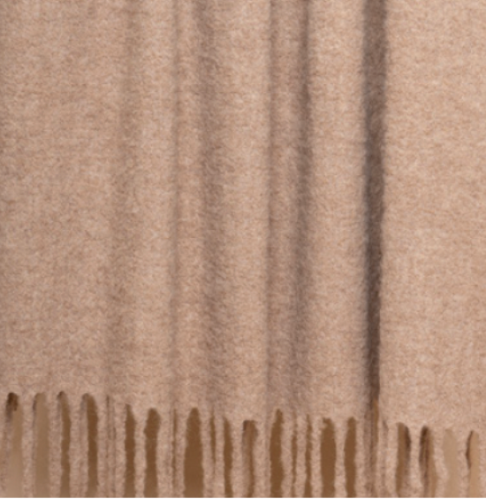 A close-up of the Thread & Butter Brushed Boucle Throw, a beige blanket with a soft, textured finish and long, even fringe, offering a natural sheen and luxurious feel reminiscent of Baby Alpaca blankets.