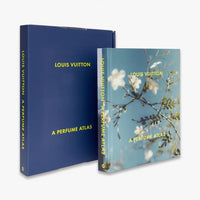 Louis Vuitton: A Perfume Atlas by W.W. Norton Company features a blue slipcase with yellow text, and a cover adorned with white and yellow flowers reflecting fragrance ingredients explored in this perfumery book.