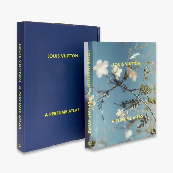Louis Vuitton: A Perfume Atlas by W.W. Norton Company features a blue slipcase with yellow text, and a cover adorned with white and yellow flowers reflecting fragrance ingredients explored in this perfumery book.