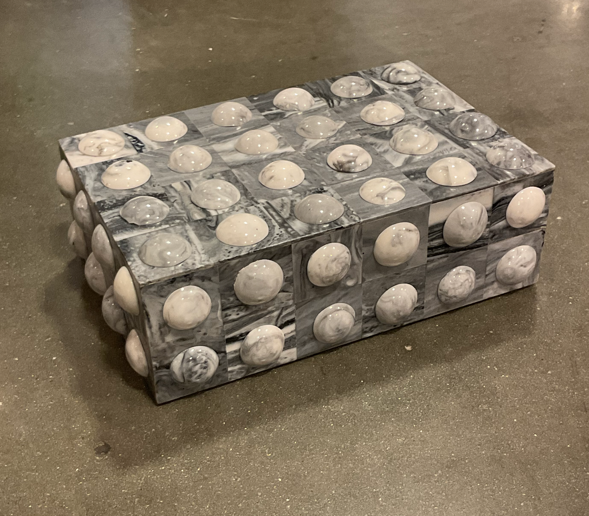 The Moondrops Grey & White Box by A Sanoma Inc is a rectangular jewelry storage box with a marbled finish and smooth dome-shaped bumps, making it a stylish decorative accent for concrete floors.