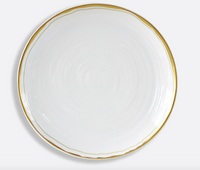 The Albatre Dinnerware - Gold by Bernardaud is a round white ceramic plate with a wavy texture and thin gold trim, showcasing wabi-sabi elegance against a light gray background.