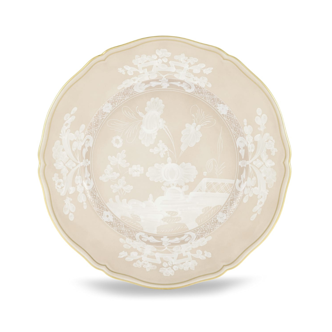 The Oriente Italiano Beige Meringa plate by Ginori 1735 is a round porcelain dinnerware piece featuring a beige background, white floral motifs, scalloped edge, and a thin gold rim.