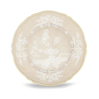 The Oriente Italiano Beige Meringa plate by Ginori 1735 is a round porcelain dinnerware piece featuring a beige background, white floral motifs, scalloped edge, and a thin gold rim.