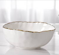 The PAMPA BAY Portofino Serving Bowl, crafted from white porcelain with a scalloped gold trim, is part of the elegant oven to table collection and sits beautifully against a soft, blurred background.