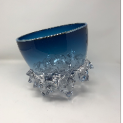 The Axiom Thorn Vessel Opal Blue - Medium 9" features a blue glass bowl with a slanted rim atop a clear, textured glass base resembling crystal clusters. Displayed against a plain white background.