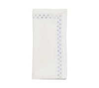 The Kim Seybert Starry Night Napkin Set of 4 in White & Blue features neatly folded white linen napkins with blue embroidered snowflake borders and delicate metallic embroidery on two edges, displayed on a plain white background.