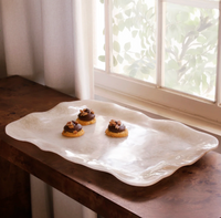 The Beatriz Ball Resin Tray Alabaster Extra Large displays three decorated cookies on a wooden surface near a window, with sheer curtains and leafy greenery visible outside.
