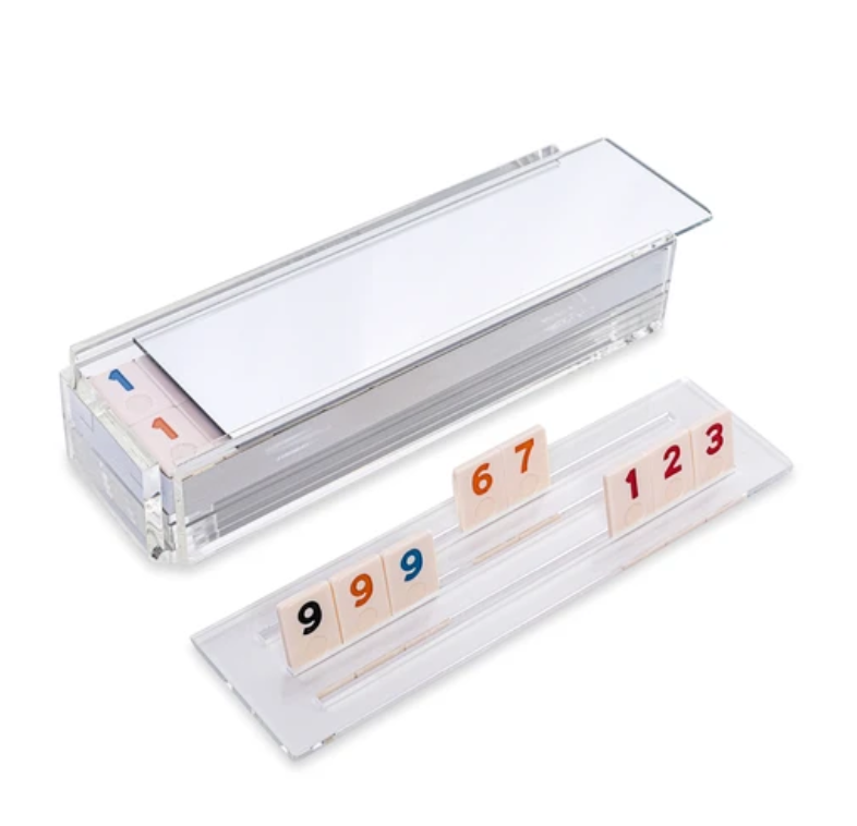 The Luxe Dominoes Rummy Acrylic Game Set features a clear acrylic tile holder and storage box to display vibrant numbered tiles—9, 9, 9, 6, 7, 1, 2, and 3—on a white background. A unique Rummikub gift for game lovers.