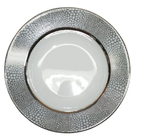 The Makassar Gray & Platinum Dinnerware by Royal Limoges/Bia Cordon Bleu is a handmade round white plate from France, crafted from Limoges porcelain with a reflective surface and a wide platinum pebble-textured rim.