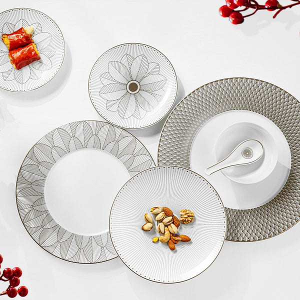 Five patterned white plates from the Malmaison Imperiale Porcelain Dinnerware Platinum collection by Christofle, each featuring a unique design, are arranged on a white surface accented with scattered nuts, a sauce dish, sushi, and red berries—offering a refined display of luxury Christofle tableware.