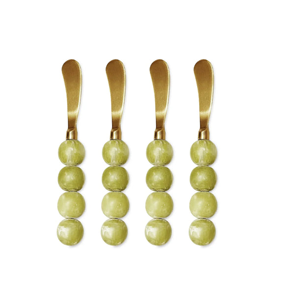 The Beatriz Ball Resin Sorbet Spreader Set of 4 in Matcha features gold butter spreaders with handles crafted from three stacked round green beads, arranged vertically side by side on a white background—perfect as unique hostess gifts or elegant additions to your charcuterie spread.