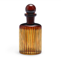 The Prism Decanter by L'Objet is a tall, elegant piece made from hand-crafted glassware with vertical ridges and a round stopper, shown against a white background.