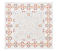 The Kim Seybert Malta Embroidered Napkin Set of 4 features white handcrafted napkins with orange, brown, and black symmetrical floral and geometric embroidery in a central circular motif.