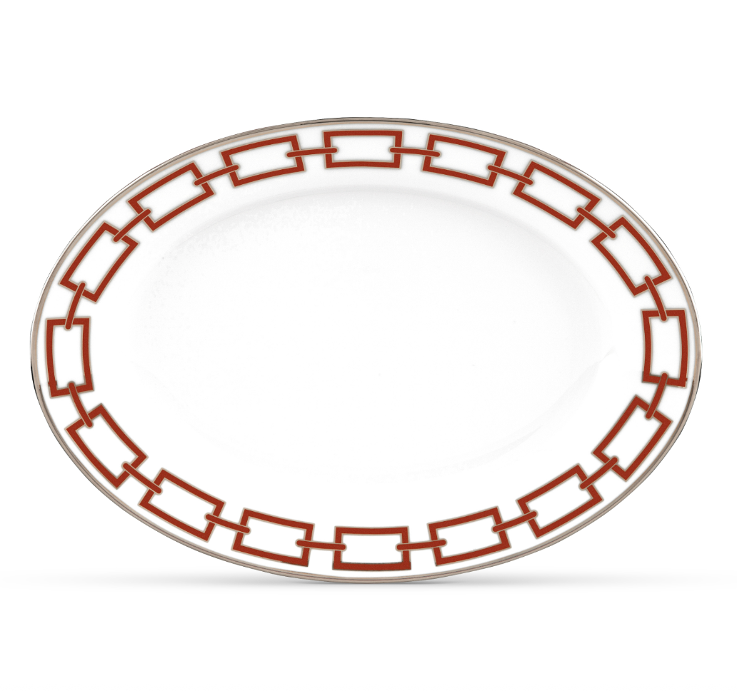 The Catene Scarlatto Dinnerware by Ginori 1735 is an oval white porcelain plate featuring a geometric red and gold border inspired by Gio Ponti, with a plain center that highlights the refined elegance of fine porcelain.