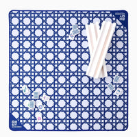 The Oh My Mahjong Travel Mini Mahjong Game Mat, sized 22” x 22”, features a blue and white pattern with logo, Mahjong tiles, and white racks displayed on the portable mat.