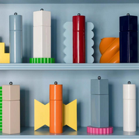 Addison Ross Mini Pillar Salt & Pepper Shakers, featuring a white lacquer finish and ceramic grinder, are displayed on blue shelves for a playful, modern look with bold colors and geometric design.