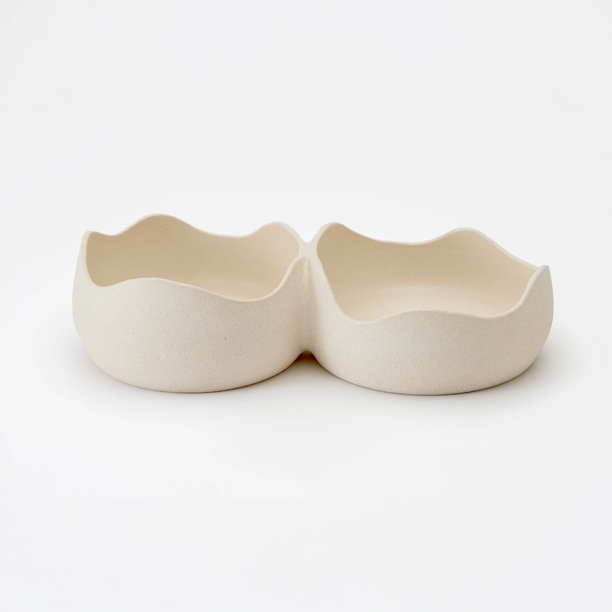 The Dumae Martina Bowl - Raw Blanc is a cream-colored ceramic dish with double compartments, wavy uneven rims, and a matte finish, shown against a plain white background.
