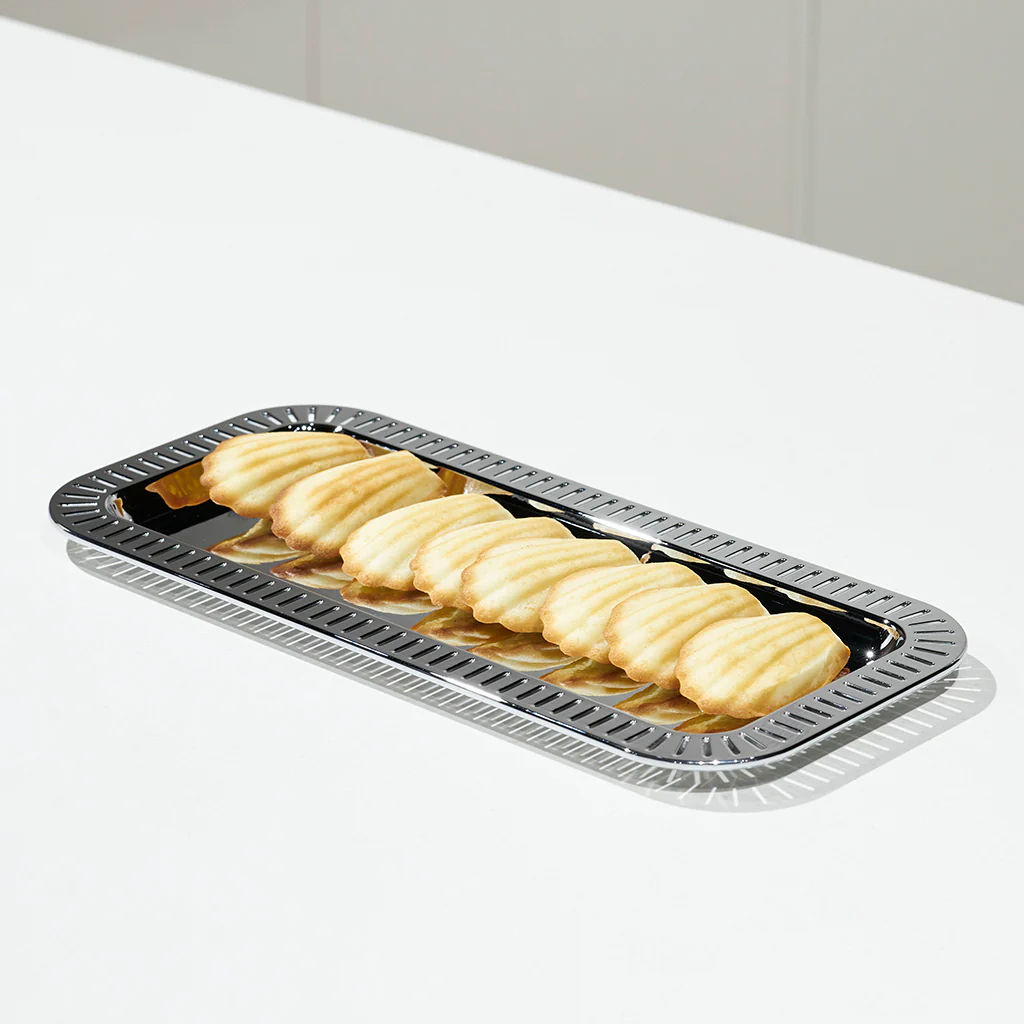 The Striations Silver Small Rectangle Serving Tray by Anna New York displays eight shell-shaped cookies in a row, set on a white surface.
