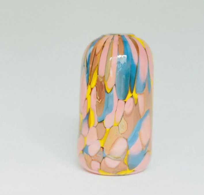 Add a unique touch to your home decor with the Jelly Baby Mini Vase Collection by Maria Ida Designs—a tall, cylindrical ceramic vase featuring a glossy finish and abstract brush-like patterns in pink, yellow, blue, and tan on a white background. This statement piece beautifully complements your glass blown mini vases or other handmade art glass objects.