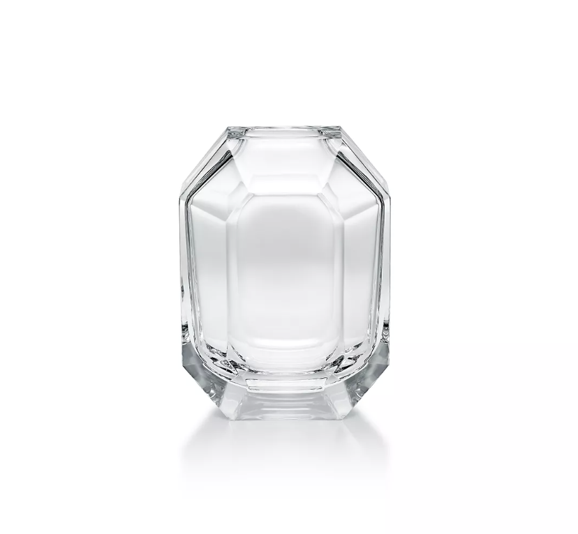 The Baccarat Octogone Bud Vase features clear, faceted glass with sharp edges and smooth surfaces, standing elegantly on a white background and reflecting the refined style of Baccarat chandeliers.