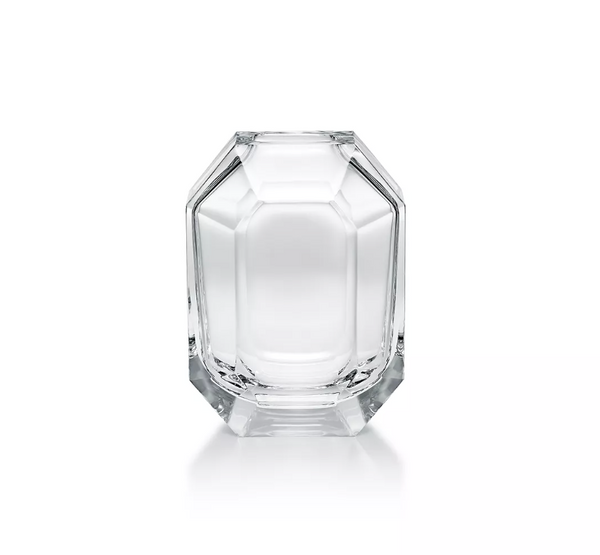 The Baccarat Octogone Bud Vase features clear, faceted glass with sharp edges and smooth surfaces, standing elegantly on a white background and reflecting the refined style of Baccarat chandeliers.