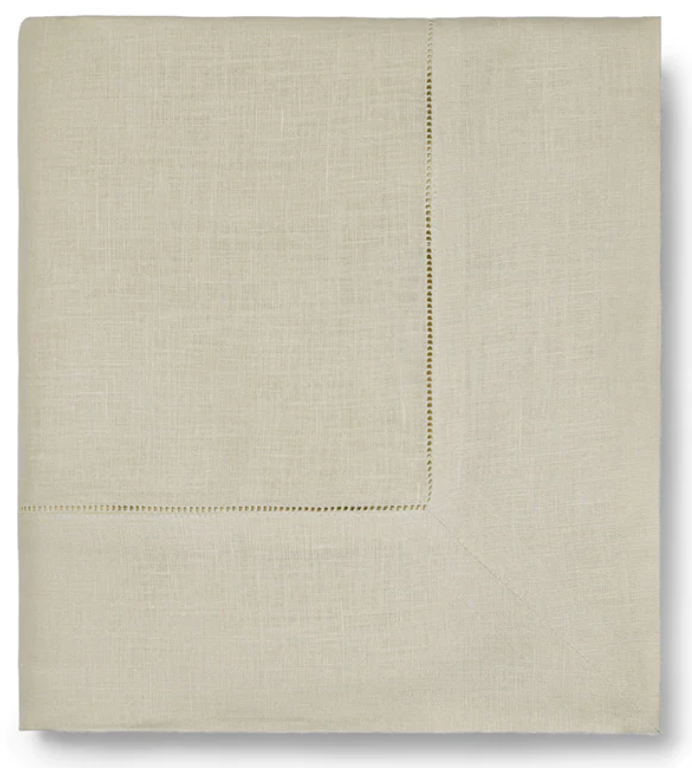 The Sferra Festival Tablecloth in light beige features a subtle hemstitch border and is elegantly displayed on a plain background.