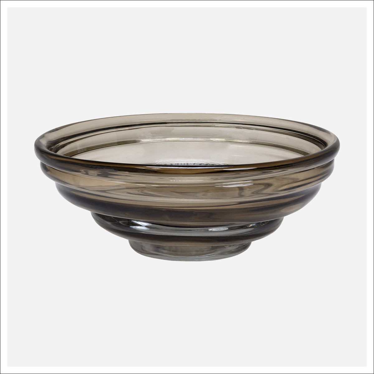 The Cameron Art Glass Bowl by Kavana is a round, shallow bowl with a smoky tint, thick rim, and sturdy base—an ideal modern centerpiece for your decor. Shown here set against a plain white background.