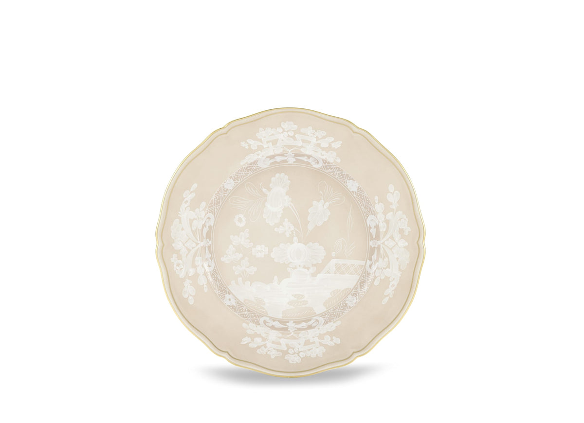 The Oriente Italiano Beige Meringa plate by Ginori 1735 is a beige ceramic piece with scalloped edges, a thin gold rim, and intricate white floral and botanical patterns inspired by the iconic porcelain dinnerware collection.