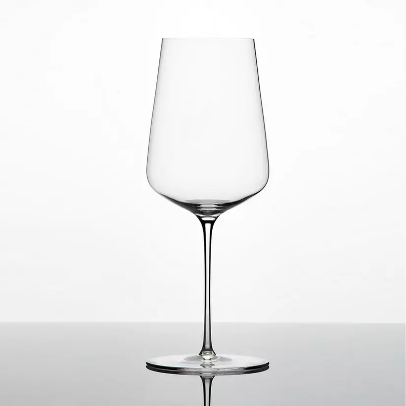 A single Zalto Universal Glass by Grand Cru Selections/Zalto, made from lead-free crystal with a long stem and wide bowl, sits on a reflective surface against a plain white background.