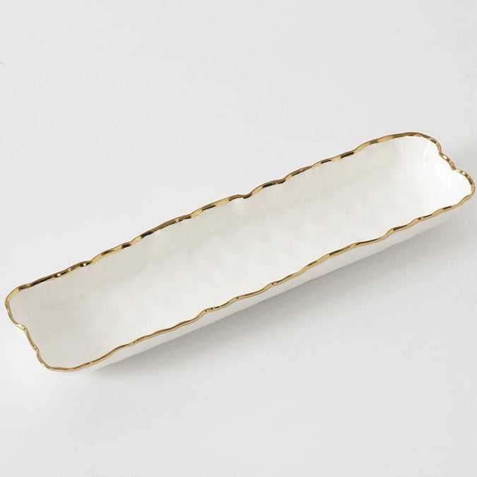 The Portofino Small Tray by PAMPA BAY is a long, rectangular porcelain serving dish with wavy edges and a metallic gold trim—an elegant, oven-safe dinnerware piece shown on a plain white background.
