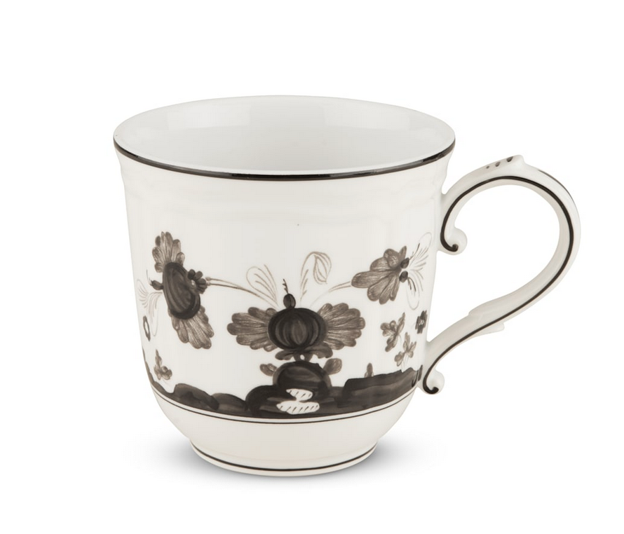 The Oriente Italiano Dinnerware Albus mug by Ginori 1735 is a white ceramic piece with a curved handle, black floral and abstract patterns, and a thin black rim, inspired by classic Italian porcelain design.