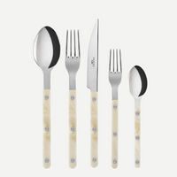 The Sabre Bistrot Horn 5 Piece Place Setting features stainless steel flatware with cream-colored handles, including a tablespoon, dinner fork, knife, salad fork, and teaspoon—displayed upright against a white background.