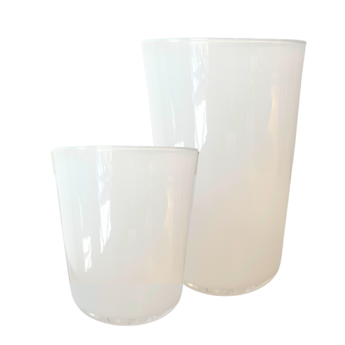Two translucent white Dynasty Cups Cotton by Gary Bodker of different heights stand side by side on a plain background, showcasing minimalist design and smooth, rounded shapes with elegant reflective surfaces.