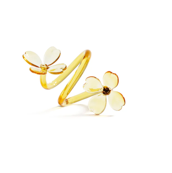 A set of four Botanica Napkin Rings by Zodax is photographed against a white background, each featuring an open spiral design with two delicate yellow flower shapes at each end. Reminiscent of sculptural napkin rings found in decorative tableware collections, these pieces evoke the elegance and artistry of glass napkin rings through their intricate floral detailing and graceful form.