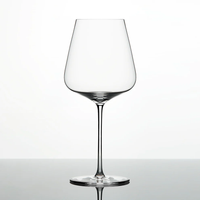 A single Grand Cru Selections / Zalto Bordeaux Glass, featuring a thin stem and wide bowl, is shown against a plain white background with its reflection visible on a glossy surface.