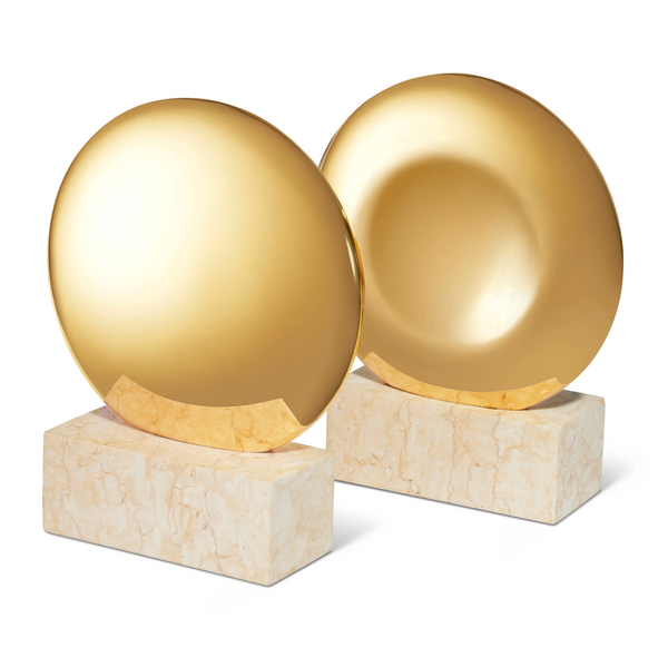 The Aerin Constantin Bookend Set of 2 features round, gold-finished discs atop rectangular marble bases. These contemporary brass bookends have a polished shine and sleek mid-century design perfect for any modern space.