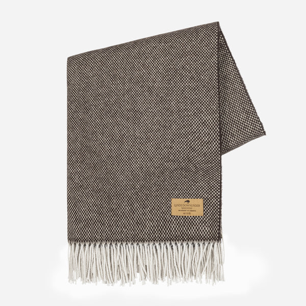 The Juno Cashmere Throw by Lands Downunder features a brown and cream herringbone pattern, white fringes, and a tan stitched label in one corner, shown against a plain white background.