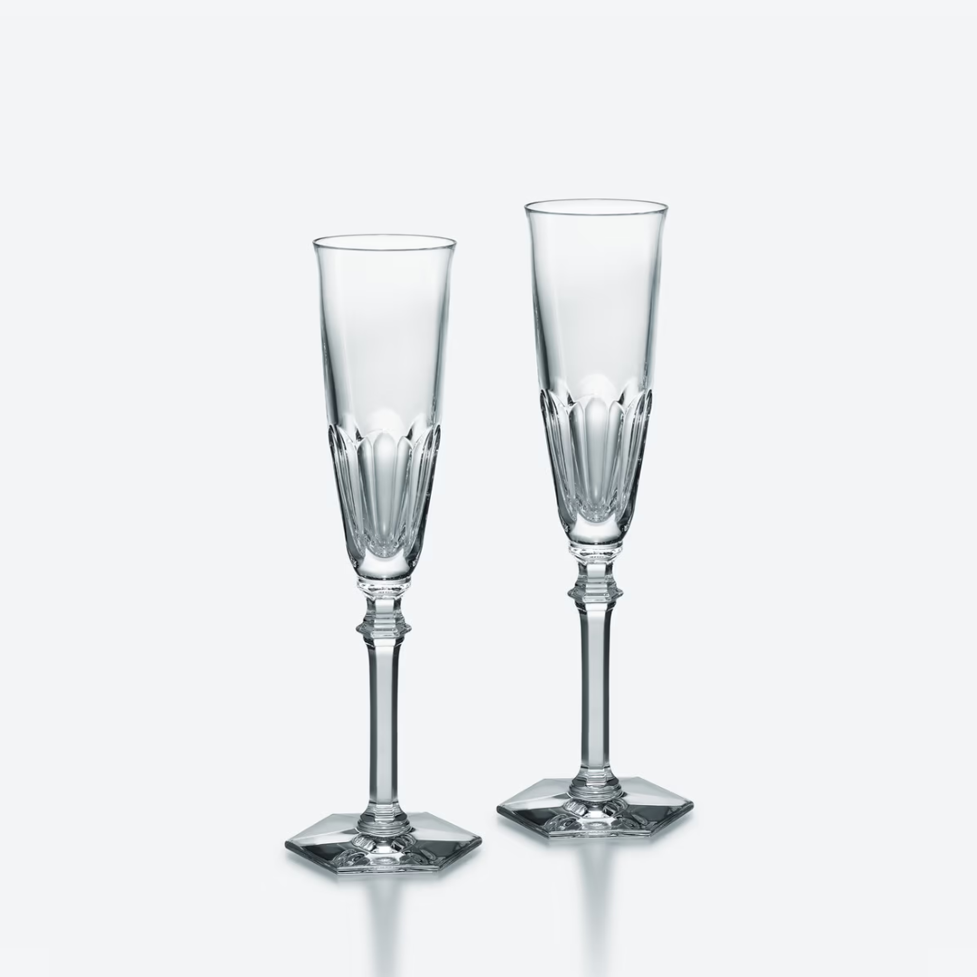 The Baccarat Harcourt Eve Flutes Set of 2 features elegant champagne glasses with hexagonal bases, shown side by side on a plain, light backdrop.