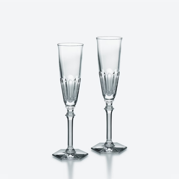 The Baccarat Harcourt Eve Flutes Set of 2 features elegant champagne glasses with hexagonal bases, shown side by side on a plain, light backdrop.