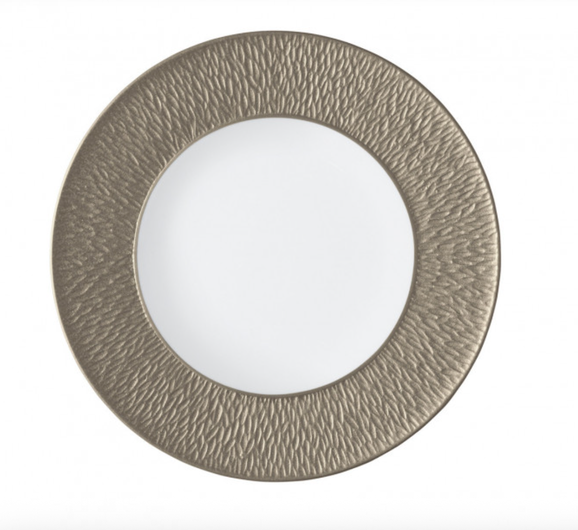 The Raynaud Mineral Irise Salad/Dessert Plate in Greige features a round white center with a wide, textured metallic gold rim, shown on a plain white background.