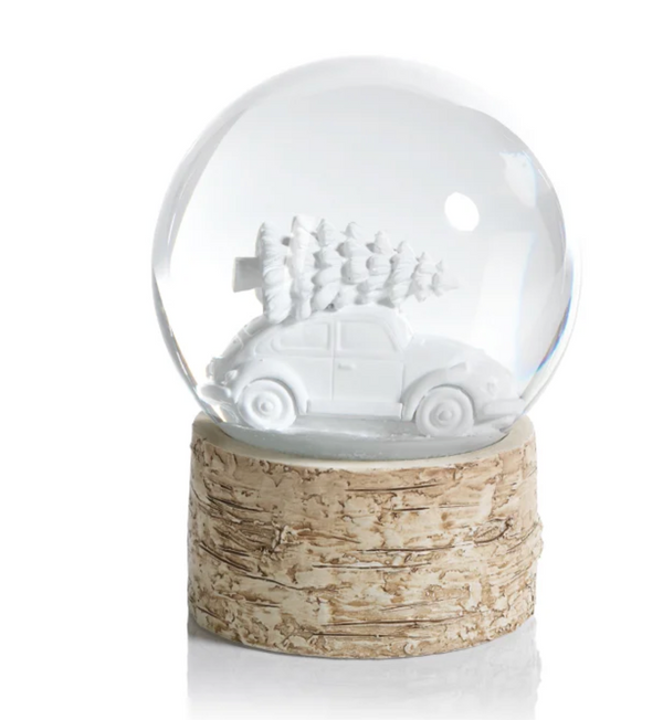 Zodax Birch Snow Globe With Car & Tree featuring a white car carrying a Christmas tree on its roof, set on a textured faux-birch base as a festive accent.